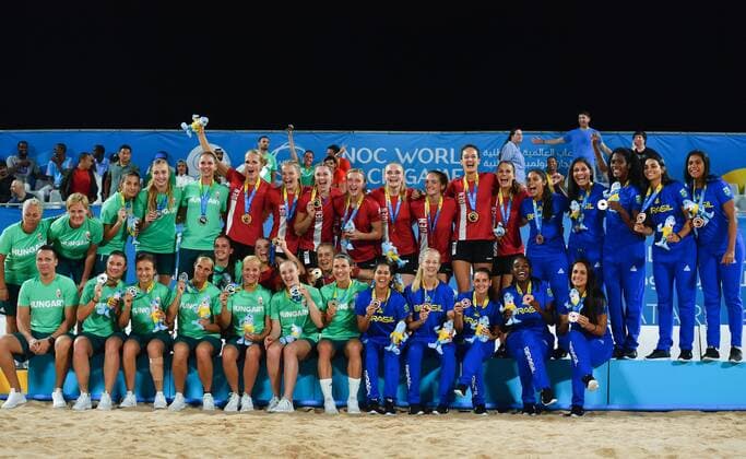 (191017) -- DOHA, Oct. 17, 2019 (Xinhua) -- Gold medalist players of Denmark (in red), silver medalist players of Hungary (in green) and bronze medalist players of Brazil (in blue) celebrate during the awarding ceremony of the women s beach handball at the 1st ANOC World Beach Games Qatar 2019 in Doha, capital of Qatar, on Oct. 16, 2019. (Photo by Nikku Xinhua) (SP)QATAR-DOHA-WORLD BEACH GAMES-BEACH HANDBALL 