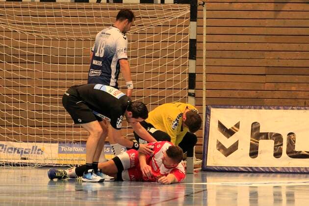 2 Bundesliga Handball VfL Luebeck Schwartau TUSEM Essen 20 10 2019, Hansehalle Luebeck, GER, 2 Bundesliga Handball VfL Luebeck Schwartau TUSEM Essen pictured picture shows injured injury pain Dennis Szczesny TUSEM Essen is lying on the ground after a collision with goalkeeper Marino Mallwitz VfL Luebeck Schwartau, left referee Kim von der Beeck nordphotox xTauchnitz nph00059