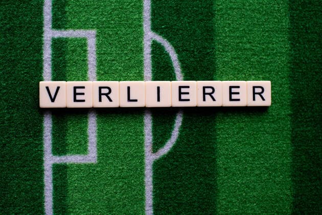 The coronavirus Covid 19 causes event cancellations of, for example, football matches of Bundesliga professionals for an indefinite period of time and many effects, in the picture The word loser on a football carpet Germany