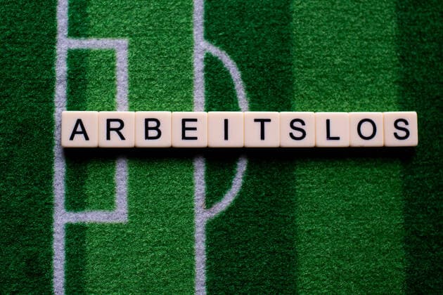 The corona virus Covid 19 causes event cancellations of, for example, football matches of Bundesliga professionals for an indefinite period of time and many effects, in the picture The word unemployed on a football carpet Germany