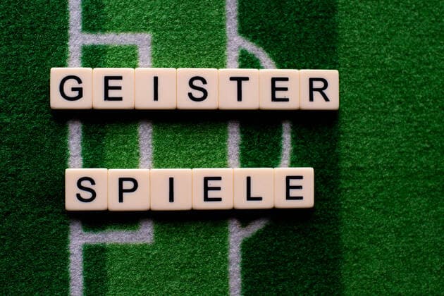 The corona virus Covid 19 causes event cancellations of, for example, football matches of Bundesliga professionals for an indefinite period of time and many effects, in the picture The word ghost games on a football carpet Germany