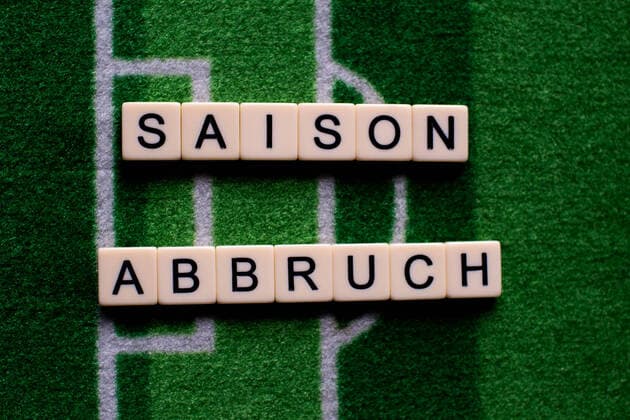 The corona virus Covid 19 causes event cancellations of, for example, soccer matches of Bundesliga professionals for an indefinite period of time and many effects, in the picture The word season end on a soccer carpet Germany