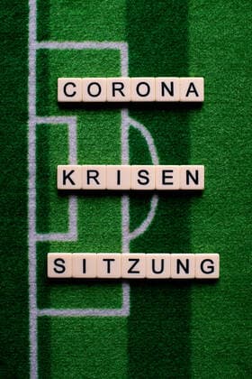 The corona virus Covid 19 causes event cancellations of, for example, football matches of Bundesliga professionals for an indefinite period of time and many effects, in the picture The word Corona crisis meeting on a football carpet Germany