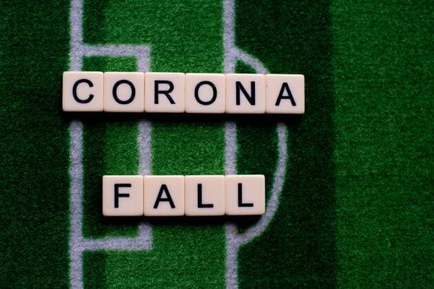 The corona virus Covid 19 causes event cancellations of, for example, football matches of Bundesliga professionals for an indefinite period of time and many effects, in the picture The word corona case on a football carpet Germany