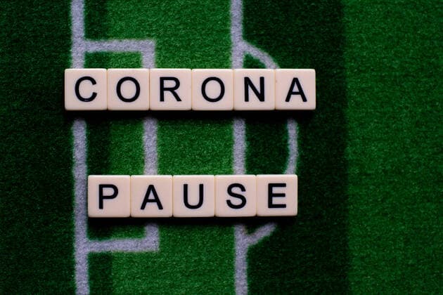 The corona virus Covid 19 causes event cancellations of, for example, football matches of Bundesliga professionals for an indefinite period of time and many effects, in the picture The word corona break on a football carpet Germany