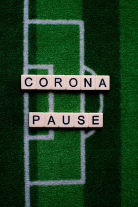 The corona virus Covid 19 causes event cancellations of, for example, football matches of Bundesliga professionals for an indefinite period of time and many effects, in the picture The word corona break on a football carpet Germany