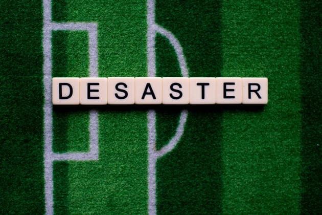 The corona virus Covid 19 causes event cancellations of, for example, football matches of Bundesliga professionals for an indefinite period of time and many effects, in the picture The word disaster on a football carpet Germany