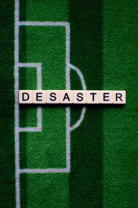 The corona virus Covid 19 causes event cancellations of, for example, football matches of Bundesliga professionals for an indefinite period of time and many effects, in the picture The word disaster on a football carpet Germany