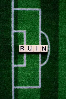 The corona virus Covid 19 causes event cancellations of, for example, football matches of Bundesliga professionals for an indefinite period of time and many effects, in the picture The word ruin on a football carpet Germany
