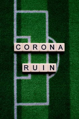 The corona virus Covid 19 causes event cancellations of, for example, football matches of Bundesliga professionals for an indefinite period of time and many effects, in the picture The word Corona Ruin on a football carpet Germany