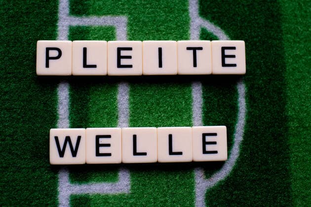 The coronavirus Covid 19 causes events such as football matches of Bundesliga professionals to be cancelled indefinitely and has many consequences, in the picture The word bankruptcy wave on a football carpet Germany