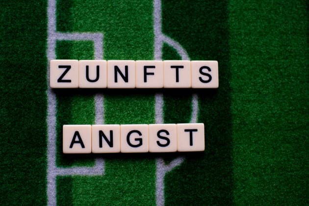 The corona virus Covid 19 causes events such as Bundesliga soccer matches to be cancelled indefinitely and has many consequences, in the picture The word fear of the future on a soccer carpet Germany