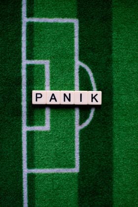 The corona virus Covid 19 causes event cancellations of, for example, football matches of Bundesliga professionals for an indefinite period of time and many effects, in the picture The word panic on a football carpet Germany
