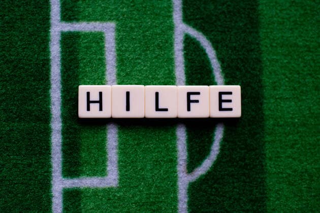 The coronavirus Covid 19 causes events such as football matches of Bundesliga professionals to be cancelled indefinitely and has many consequences, in the picture The word help on a football carpet Germany
