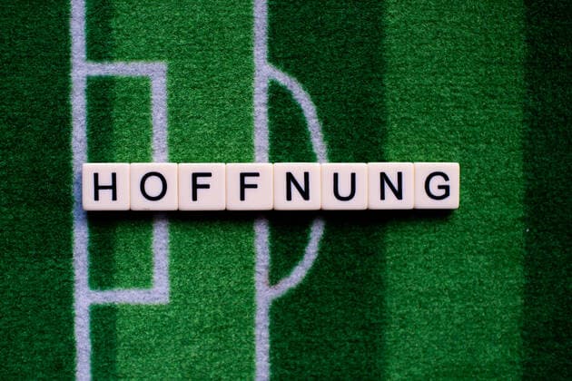 The corona virus Covid 19 causes event cancellations of, for example, football matches of Bundesliga professionals for an indefinite period of time and many effects, in the picture The word hope on a football carpet Germany