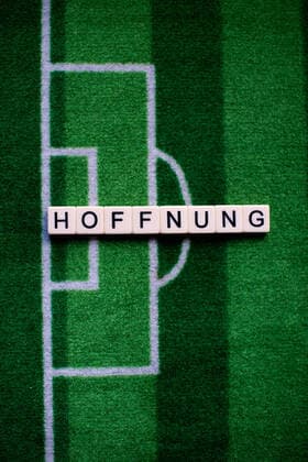 The corona virus Covid 19 causes event cancellations of, for example, football matches of Bundesliga professionals for an indefinite period of time and many effects, in the picture The word hope on a football carpet Germany
