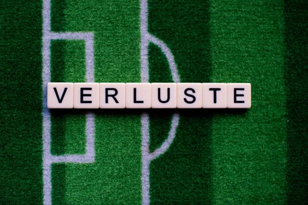 The coronavirus Covid 19 causes event cancellations of, for example, football matches of Bundesliga professionals for an indefinite period of time and many effects, in the picture The word losses on a football carpet Germany