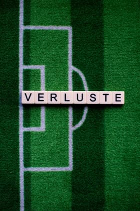 The coronavirus Covid 19 causes event cancellations of, for example, football matches of Bundesliga professionals for an indefinite period of time and many effects, in the picture The word losses on a football carpet Germany