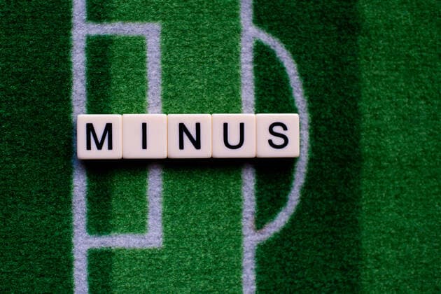 The corona virus Covid 19 causes event cancellations of, for example, football matches of Bundesliga professionals for an indefinite period of time and many effects, in the picture The word minus on a football carpet Germany