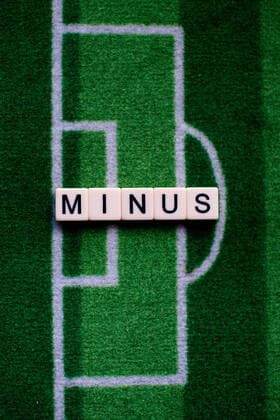 The corona virus Covid 19 causes event cancellations of, for example, football matches of Bundesliga professionals for an indefinite period of time and many effects, in the picture The word minus on a football carpet Germany