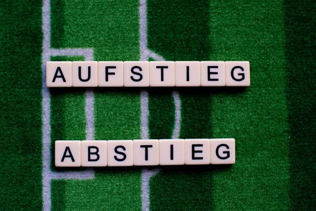 The corona virus Covid 19 causes event cancellations of, for example, football matches of Bundesliga professionals for an indefinite period of time and many effects, in the picture The word rise and fall on a football carpet Germany