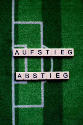 The corona virus Covid 19 causes event cancellations of, for example, football matches of Bundesliga professionals for an indefinite period of time and many effects, in the picture The word rise and fall on a football carpet Germany