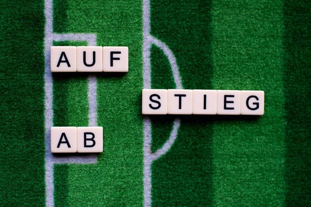The corona virus Covid 19 causes event cancellations of, for example, football matches of Bundesliga professionals for an indefinite period of time and many effects, in the picture The word rise and fall on a football carpet Germany