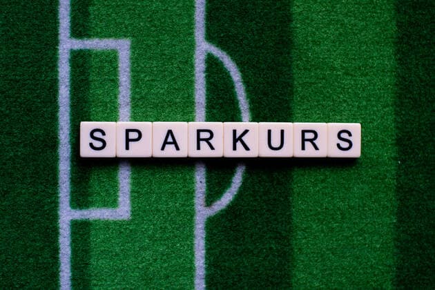 The corona virus Covid 19 causes event cancellations of, for example, football matches of Bundesliga professionals for an indefinite period of time and many effects, in the picture The word savings course on a football carpet Germany