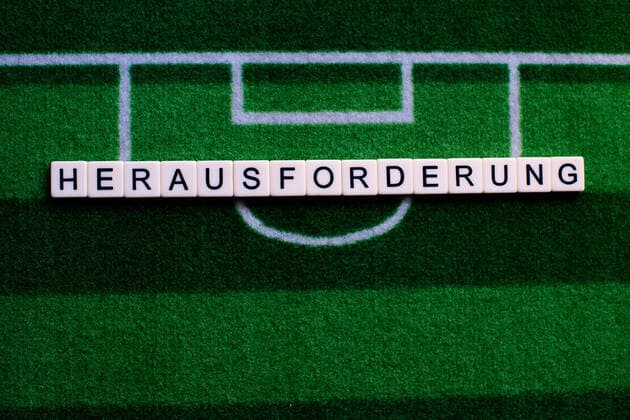 The corona virus Covid 19 causes event cancellations of, for example, football matches of Bundesliga professionals for an indefinite period of time and many effects, in the picture The word challenge on a football carpet Germany