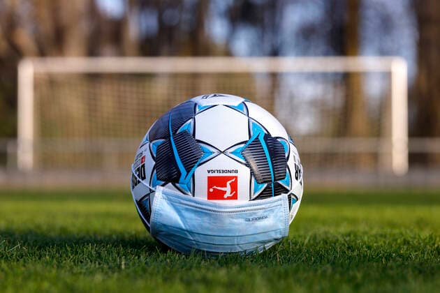 Der offizielle Spielball der Bundesliga Derbystar liegt mit Mundschutz auf einem Fußballplatz. Köln, 11.04.2020 *** The official match ball of the Bundesliga Derbystar is lying on a football field with a face mask Cologne, 11 04 2020 Foto:xC.xHardtx xFuturexImage