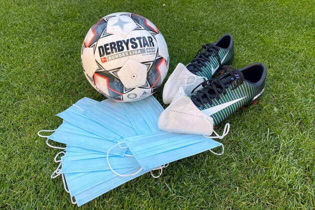 Theme photo Coronavirus pandemic effects on football Mouth masks, masks are placed in front of a DERBYSTAR match ball, ball and a pair of football boots Feature, edge motif, general