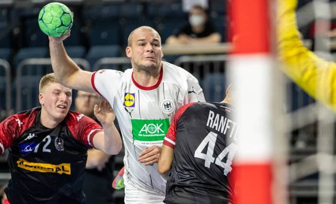 Koeln, 10 01 21, European Handball Championship, 4 Matchday, Qualification, Lanxess Arena Germanys Paul Drux M throws the ball on goal against Lukas Hutecek l and Julian Ranftl of Austria Due to the measures to contain the Corona virus, the match will take place without spectators Germany Austria