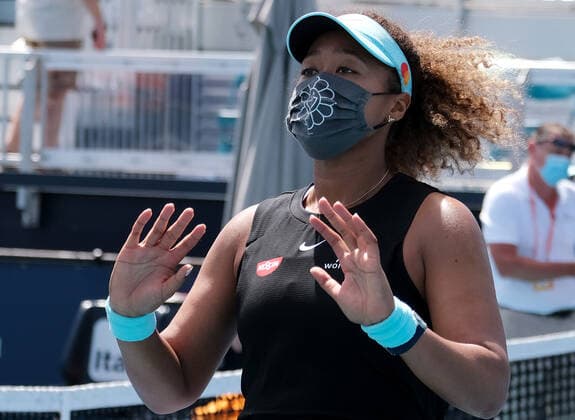 Naomi Osaka from Japan puts on a mask and waves to friends in the stands after defeating Ajla Tomljanovic from Australia on the stadium court at the Miami Open at Hard Rock Stadium in Miami Gardens, Florida on Friday, March 26, 2021.  MIA20210326115 GARYxIxROTHSTEIN