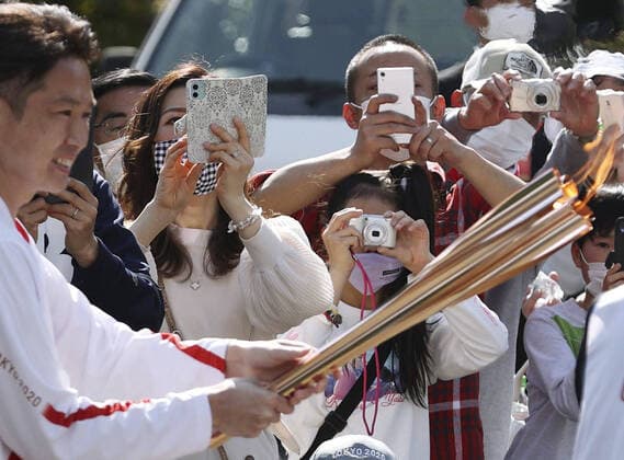 Tokyo Olympic torch relay Spectators take photos of a Tokyo Olympic torch relay runner holding the Olympic flame in Sakurai in Nara Prefecture, western Japan, on April 11, 2021. 