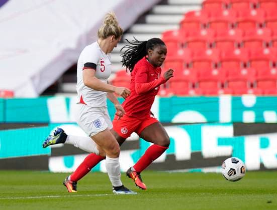 Stoke, England, 13th April 2021. Deanne Rose of Canada bursts forward past Millie Bright of England during the International Football Friendly match at The Bet365 Stadium, Stoke. Picture credit should read: Andrew Yates Sportimage EDITORIAL USE ONLY. No use with unauthorised audio, video, data, fixture lists, club league logos or live services. Online in-match use limited to 120 images, no video emulation. No use in betting, games or single club league player publications. SPI-0999-0005