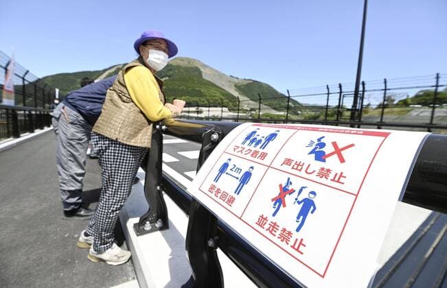 Tokyo Olympic torch relay Photo taken in the Kumamoto Prefecture village of Minamiaso, southwestern Japan, on May 6, 2021, shows a roadside sign asking Tokyo Olympic torch relay spectators to take anti-coronavirus measures during the relay amid the virus pandemic. 