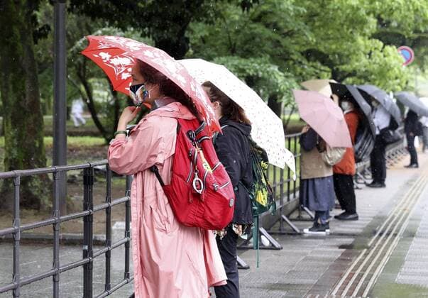 Downscaled Olympic torch relay in Hiroshima People standing behind a fence watch an ignition ceremony for the Tokyo Olympic torch relay at Peace Memorial Park in Hiroshima, western Japan, on May 17, 2021. The torch relay was taken off public roads in Hiroshima with a coronavirus state of emergency in place and spectators were not allowed at the ceremony. 