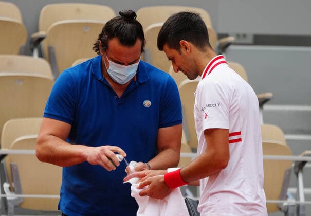 (210608) -- PARIS, June 8, 2021 -- A staff member helps Novak Djokovic (R) of Serbia with his injury during the men s singles fourth round match between Novak Djokovic of Serbia and Lorenzo Musetti of Italy at the French Open tennis tournament at Roland Garros in Paris, France, June 7, 2021. ) (SP)FRANCE-PARIS-TENNIS-ROLAND GARROS-FRENCH OPEN-DAY 9 GaoxJing 