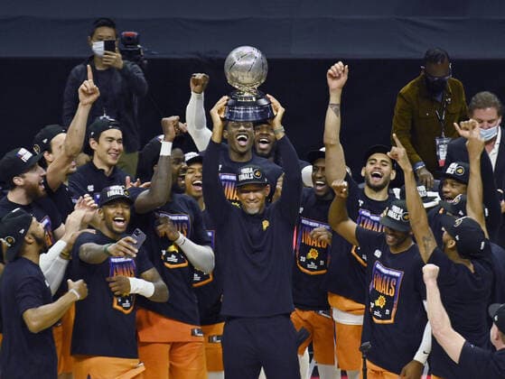 Suns coach Monty Williams holds up the trophy surrounded by team members of the Phoenix Suns after defeating the Los Angeles Clippers 130-103 in Game 6 of the Western Conference finals at Staples Center in Los Angeles on Wednesday, June 30, 2021.  LAP2021063002 JIMxRUYMEN