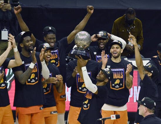 Phoenix Suns guard Chris Paul holds up the trophy surrounded by his teammates after defeating the Los Angeles Clippers 130-103 in Game 6 of the Western Conference finals at Staples Center in Los Angeles on Wednesday, June 30, 2021.  LAP2021063001 JIMxRUYMEN