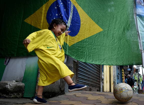India: Brazil Football supporter support their team ahead of Copa America final in Kolkata A toddler wearing Brazil football jersey playing football next to a Brazil national flag ahead of Copa America Football final match between Brazil and Argentina in Kolkata. Kolkata West Bengal India Copyright: SudiptaxDas