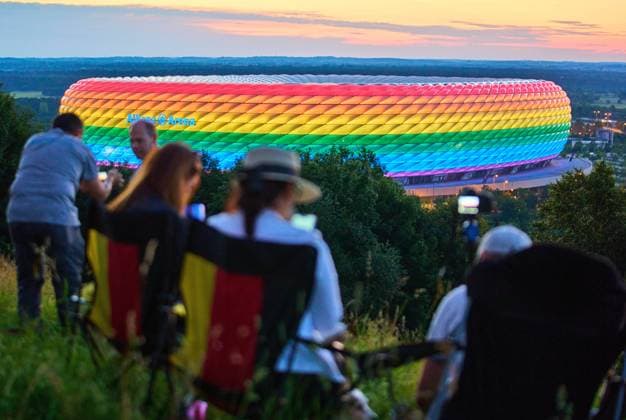 People on the Fröttmaninger Müllberg on the occasion of Christopher Street Day in Munich, the Allianz Arena is illuminated in rainbow colors, which symbolize the colors of the LBGTQ movement in Munich. Bavaria, Germany, July 10, 2021. LGBTQ stands for lesbian, gay, bisexual, transgender, and questioning (or queer).
