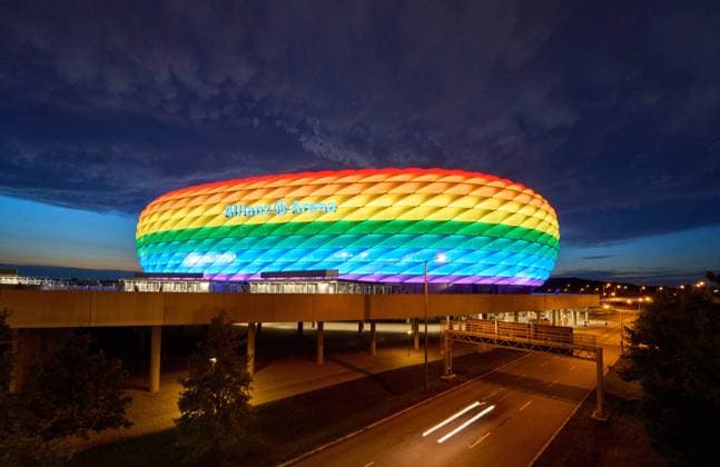 People on the Fröttmaninger Müllberg on the occasion of Christopher Street Day in Munich, the Allianz Arena is illuminated in rainbow colors, which symbolize the colors of the LBGTQ movement in Munich. Bavaria, Germany, July 10, 2021. LGBTQ stands for lesbian, gay, bisexual, transgender, and questioning (or queer).