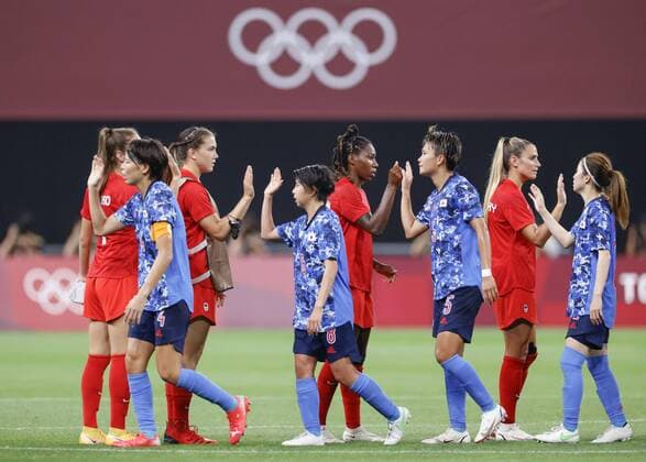 Tokyo Olympics: Football Players of Japan (blue) and Canada (red) exchange high-fives after a 1-1 draw in their Group E match of the Tokyo Olympic women s football tournament on July 21, 2021, at Sapporo Dome in northern Japan.  A14AA0000753392P