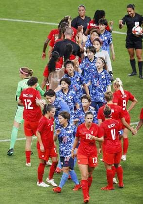 Tokyo Olympics: Football Players of Japan (blue) and Canada (red) exchange high-fives after a 1-1 draw in their Group E match of the Tokyo Olympic women s football tournament on July 21, 2021, at Sapporo Dome in northern Japan.  A14AA0000753393P