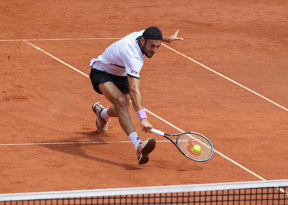 Stefano Travaglia plays a low forehand volley at the net Copyright: xJuergenxHasenkopfx