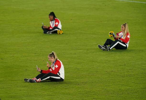 August 7, 2021, Yokohama, Japan: Canadian soccer players sit on the field and talk with family and friends as they celebrate their win against Sweden in the women s soccer gold medal game at the Tokyo Olympics in Yokohama, Japan on Friday, August 6, 2021. Canada News - August 7, 2021  - ZUMAc35_ 20210807_zaf_c35_013 Copyright: xAdrianxWyldx
