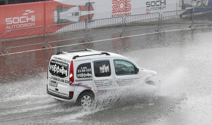 SOCHI, RUSSIA - SEPTEMBER 25, 2021: A car moves in the rain at a parking lot by a paddock area at the Sochi Autodrom racing circuit hosting the 2021 Formula One Russian Grand Prix. The third practice session of the 2021 F1 Russian Grand Prix has been canceled amid heavy rains in Sochi. Sergei Fadeichev TASS  TS111E2C