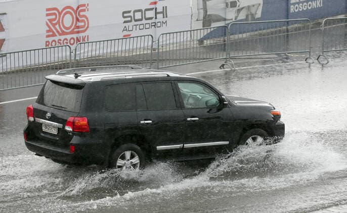 SOCHI, RUSSIA - SEPTEMBER 25, 2021: A car moves in the rain at a parking lot by a paddock area at the Sochi Autodrom racing circuit hosting the 2021 Formula One Russian Grand Prix. The third practice session of the 2021 F1 Russian Grand Prix has been canceled amid heavy rains in Sochi. Sergei Fadeichev TASS  TS111E2E