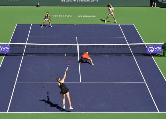INDIAN WELLS, CA - OCTOBER 16: Elena Rybakina of Kazakhstan serves the ball to Elise Mertens of Belgium while Mertens partner Su-Wei Hsieh of Chinese Taipei looks on and Rybakina s partner Veronika Kubermetova of Russia stays low near the net during a finals doubles tennis match played on October 16, 2021 at the BNP Paribas Open at the Indian Wells Tennis Garden in Indian Wells, CA. (Photo by John Cordes Icon Sportswire) TENNIS: OCT 16 BNP Paribas Open Icon506211016028